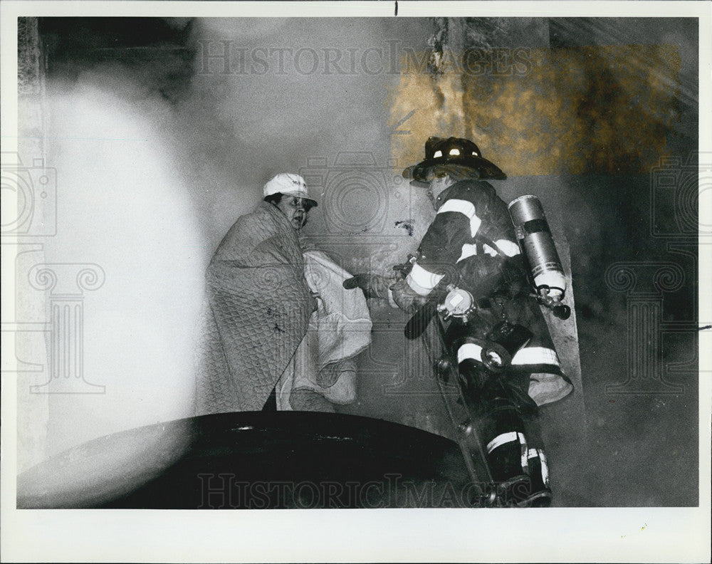 1983 Press Photo Firefighter saving a woman from a burning building - Historic Images