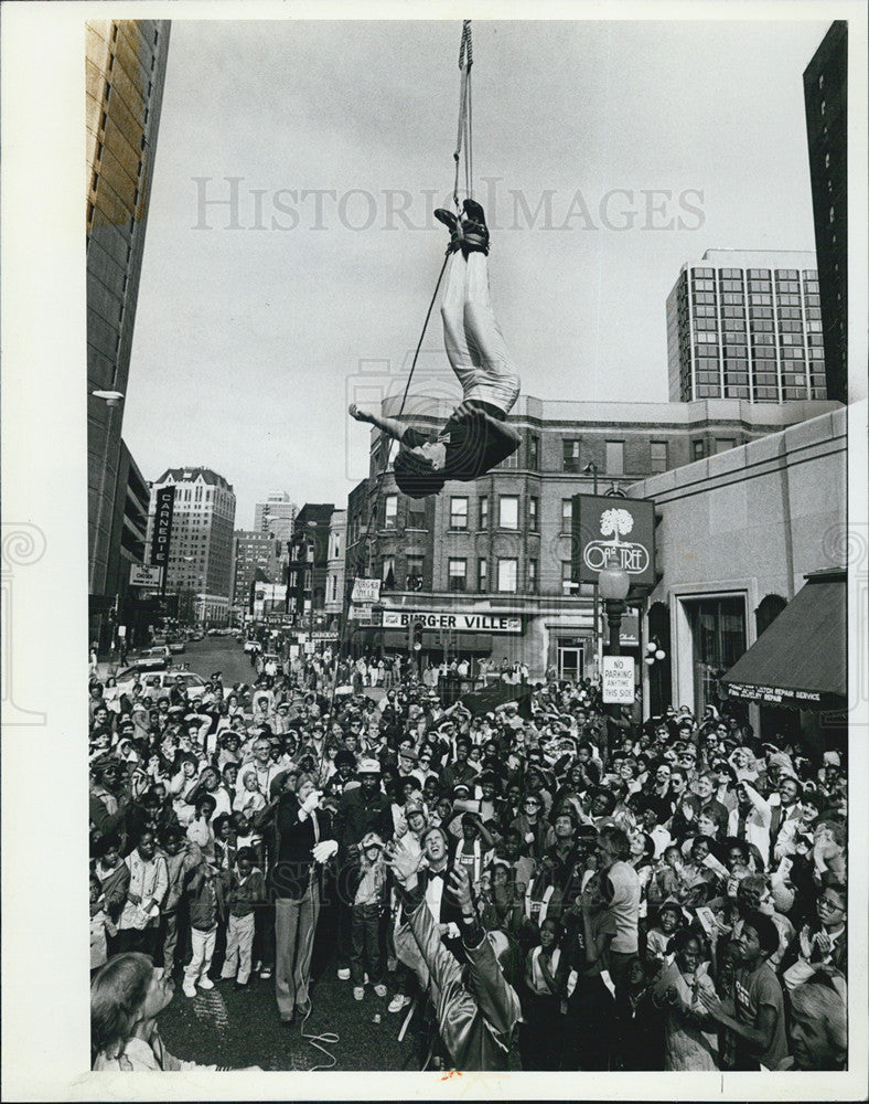 1982 Press Photo The Great Rosso hangs upside down from a ceane attached a burning rope - Historic Images