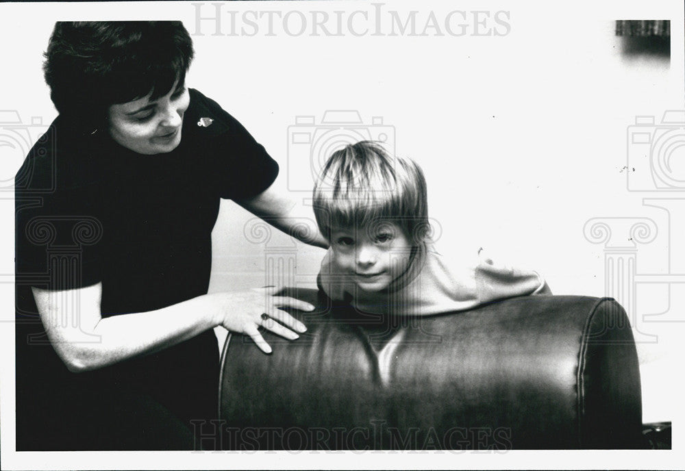 Press Photo A Woman Holds Onto A Boy As He Climbs On Furniture - Historic Images