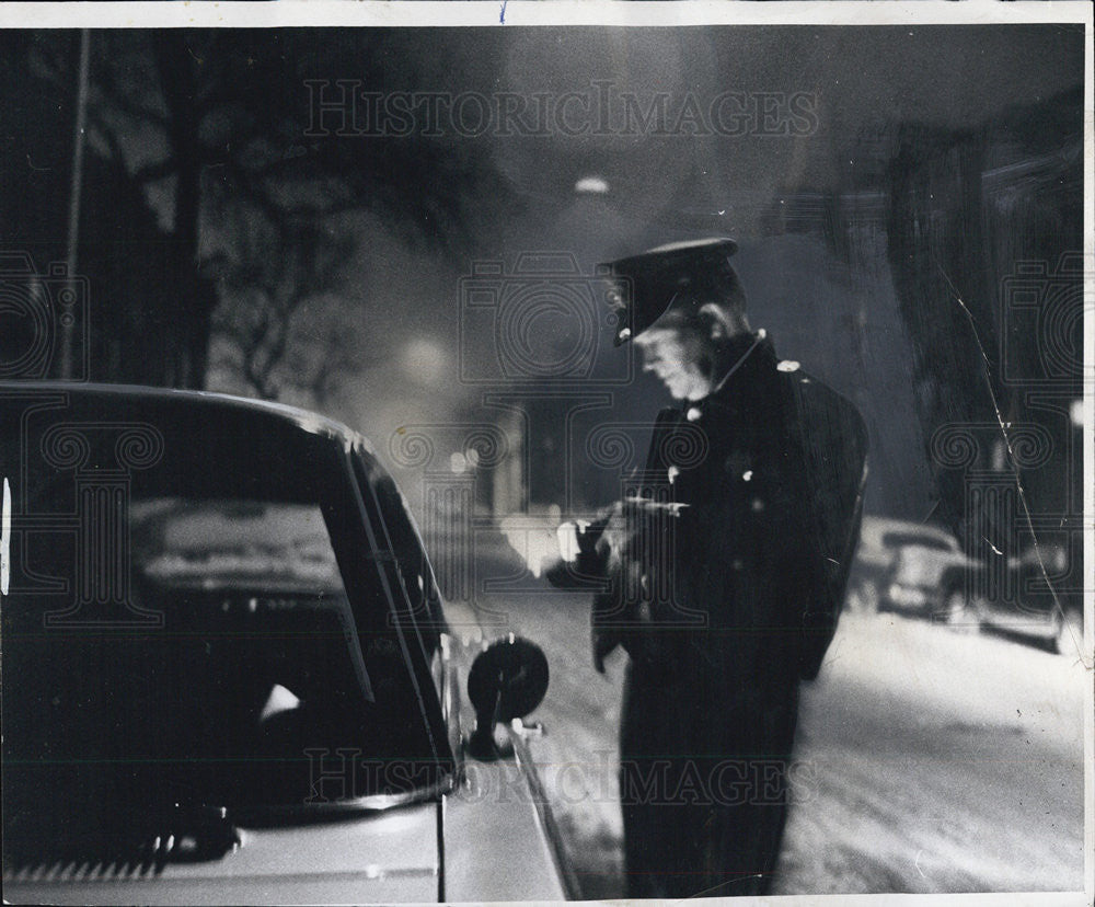 1968 Press Photo Policeman  flashlight a parked car but the motor is running. - Historic Images