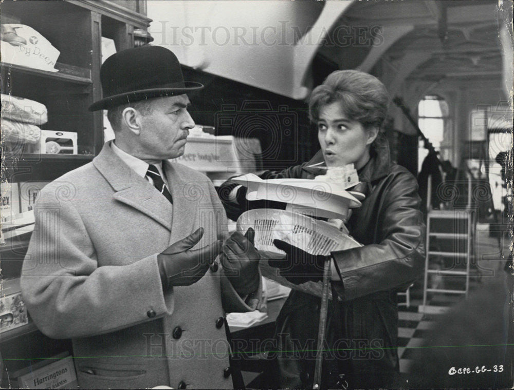 Press Photo A man in a coat talking with a Lady carrying items - Historic Images