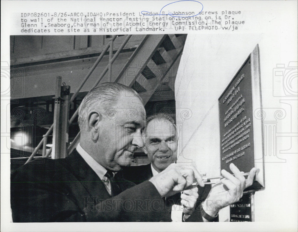 1966 Press Photo Pres Johnson screws plaque to wall at the National Reactor Testing Station - Historic Images