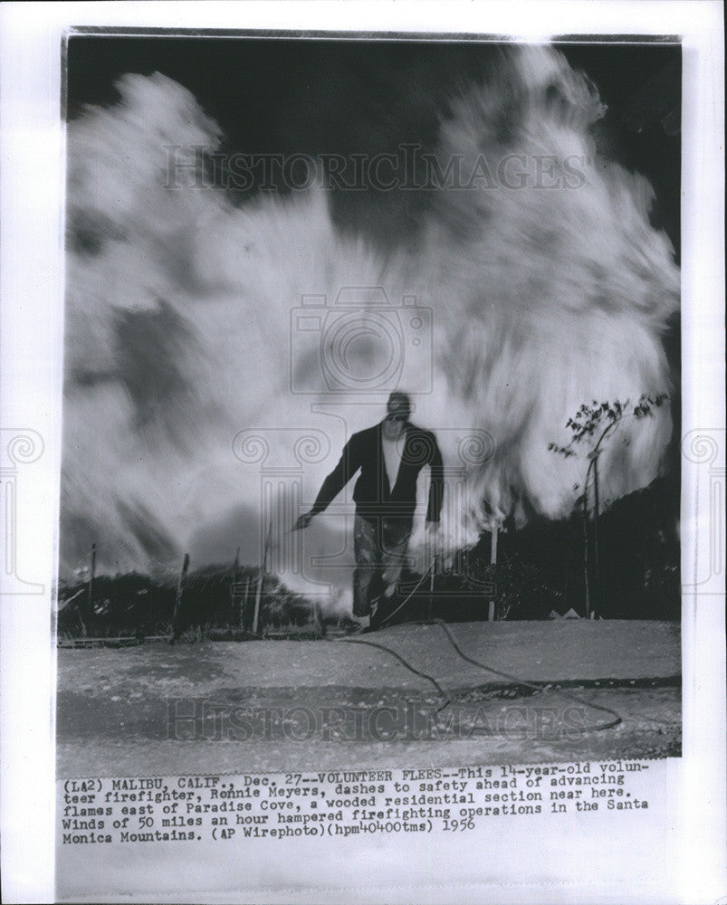 1956 Press Photo Volunteer Firefighter dashes to safety ahead of Flames. - Historic Images