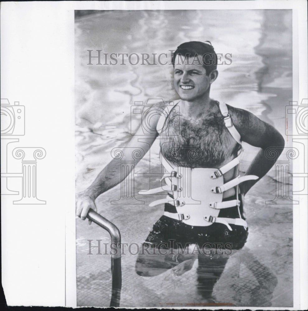 1965 Sen. Ted Kennedy in a pool with a back brace on - Historic Images