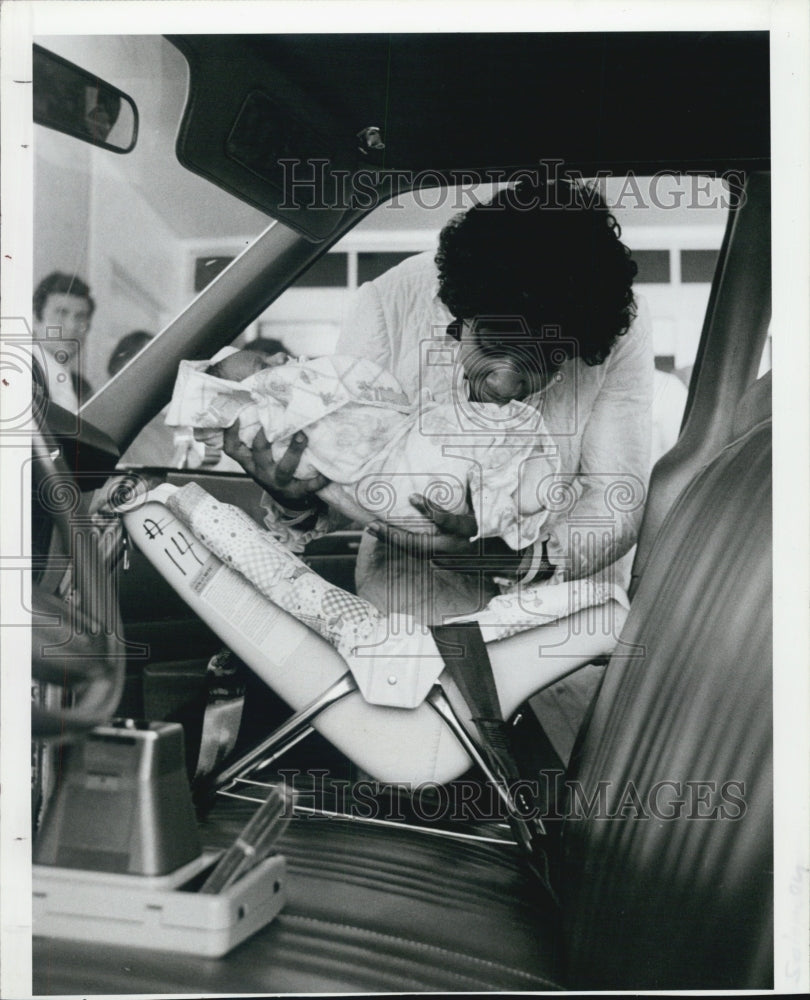 1983 Press Photo Aileen Solomann puts Jessica Salomann in her car seat. - Historic Images