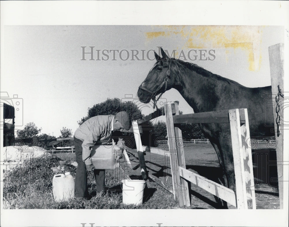 1988 Press Photo Art TThompson unloads jugs of water for his horses - Historic Images