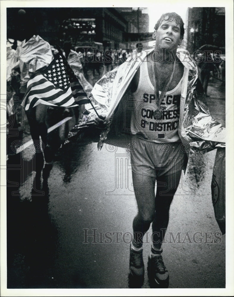 1986 Press Photo Exhausted Marathon Runner Waves American Flag Finish Line - Historic Images