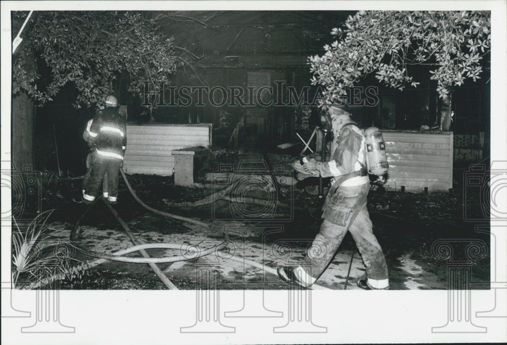 1987 Press Photo of firefighter investigating arson of home at 201 Fourth St. - Historic Images