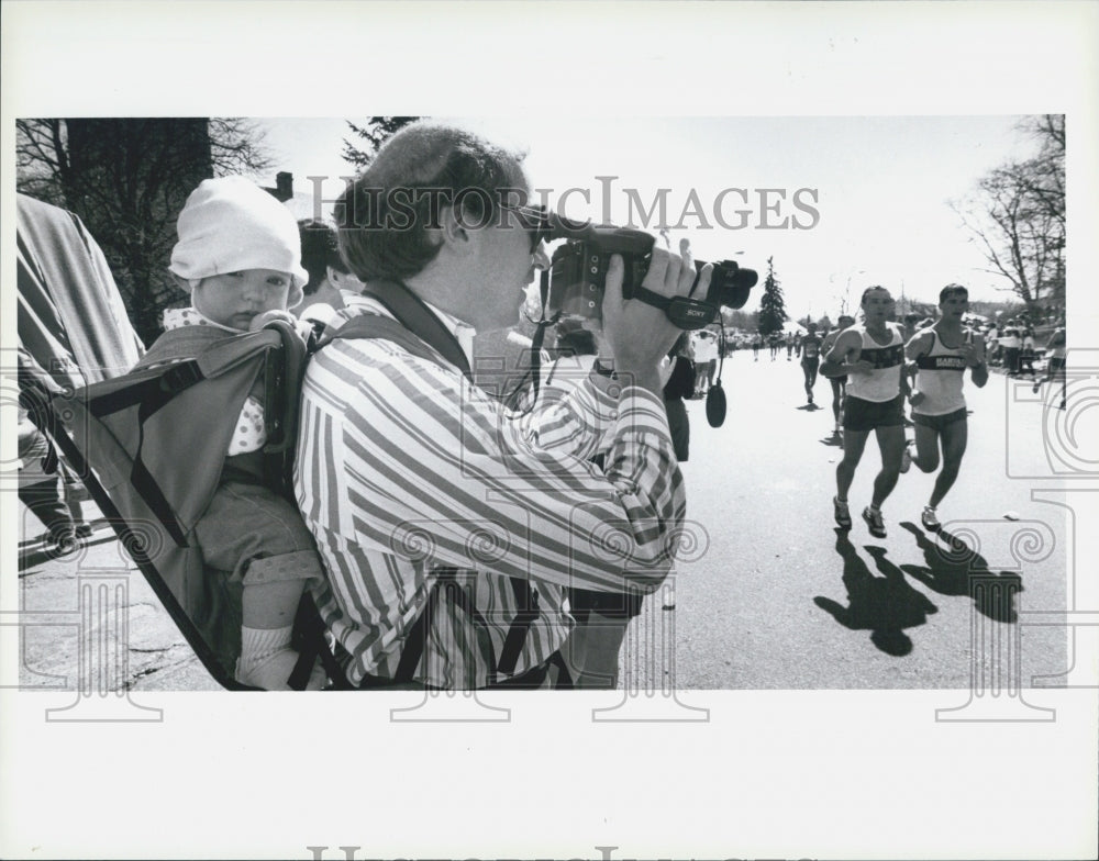 1989 Press Photo of baby Eliza Badham watching Boston Marathon while dad records - Historic Images