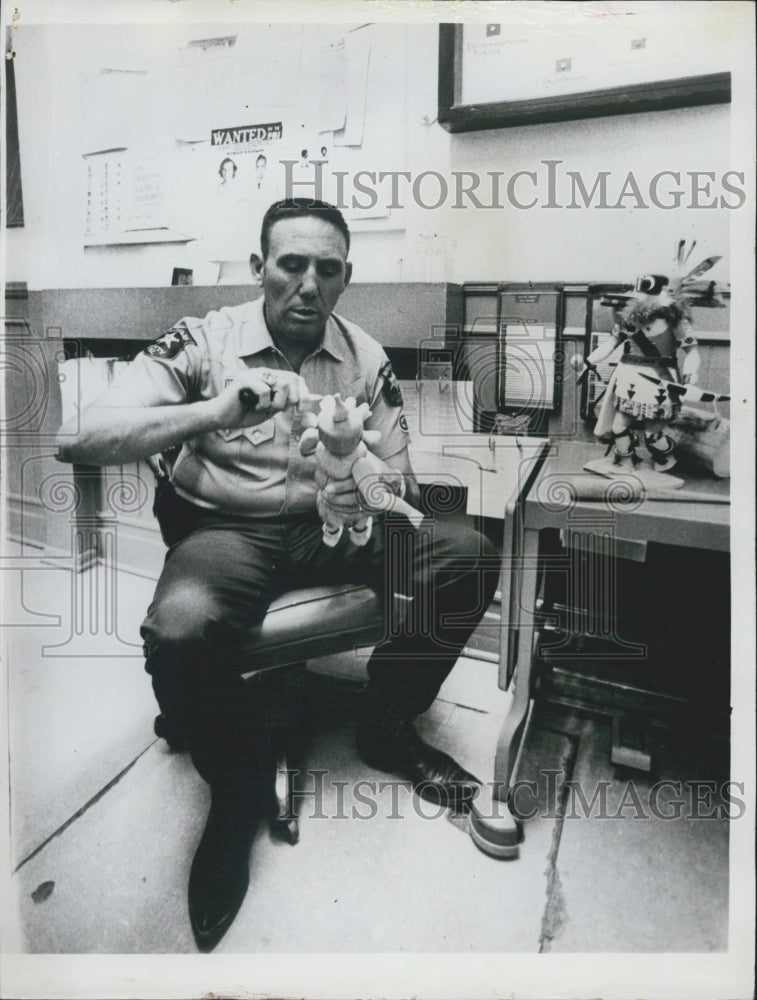 Press Photo Police man and doll in office sitting on a chair - Historic Images