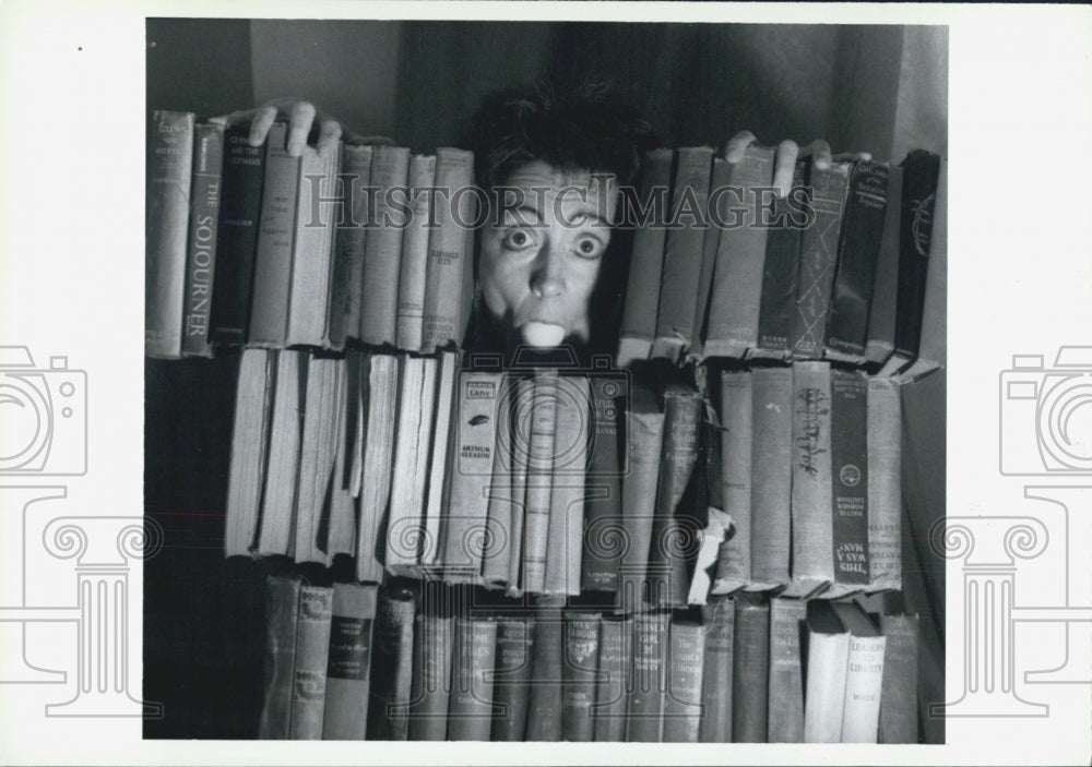 Press Photo Person hiding behind stacks of books - Historic Images