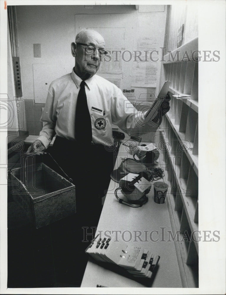 1974 Mr. Castoaguay at office holding a basket and looking at paper-Historic Images