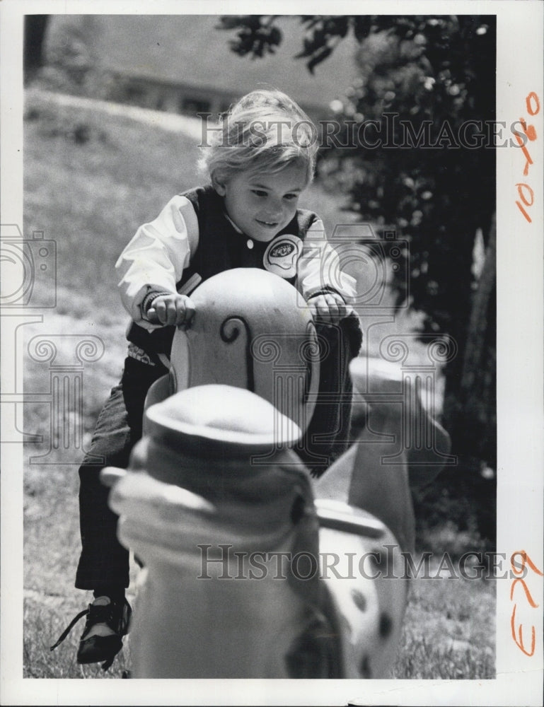 1975 Derald Stamper bouncing with animal toy. - Historic Images