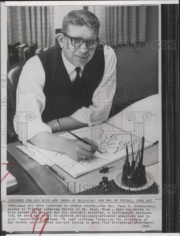 1963 The Rev. Paul E. Schuessler uses his hobby of cartoons to - Historic Images