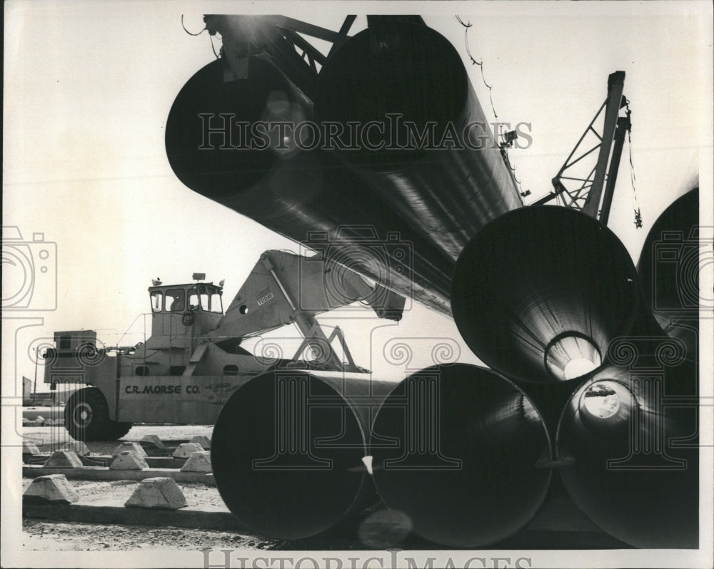 1977 Press Photo A lifting vehicle stacks pipes to used for oil pipeline - Historic Images
