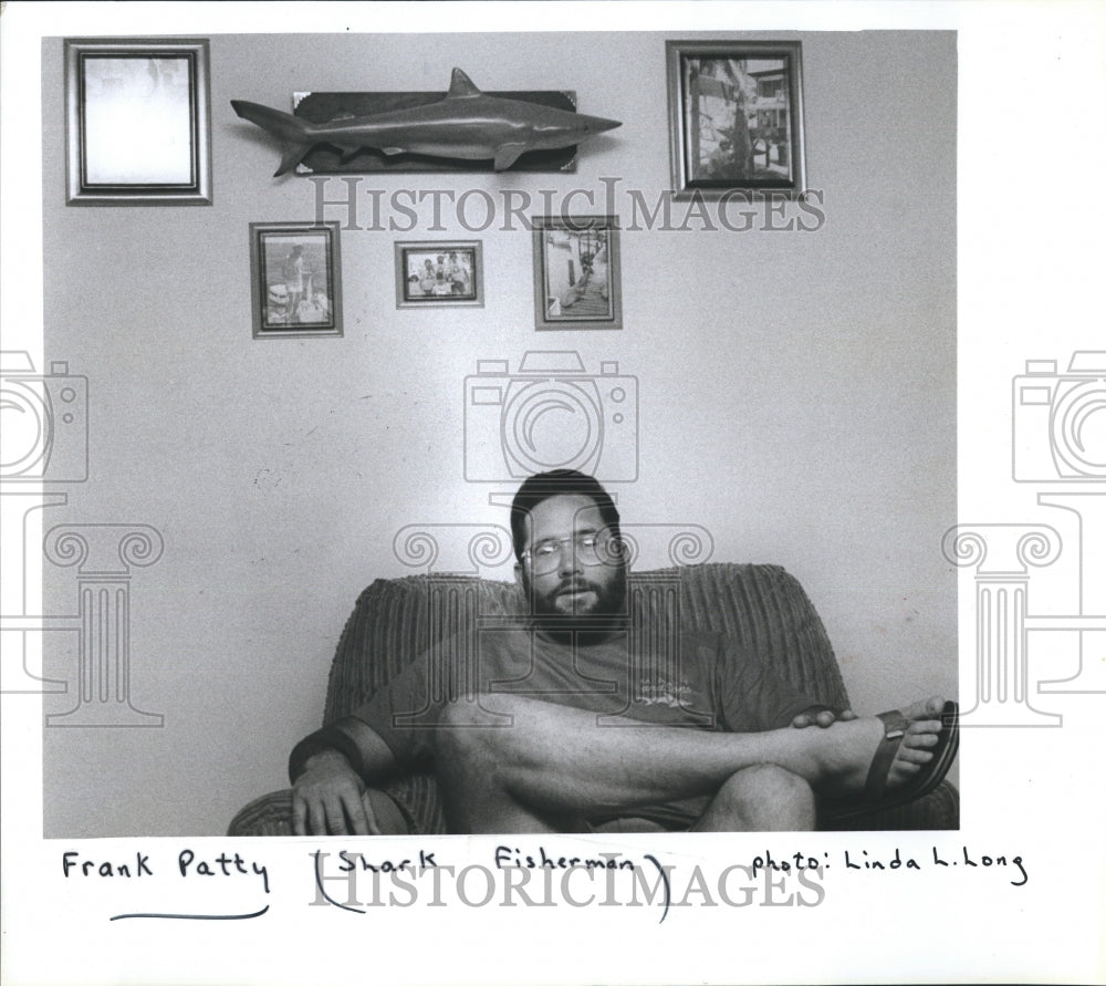 1986 Press Photo Shark Fisherman Frank Patty Sits Easy Chair Surrounded Photos - Historic Images