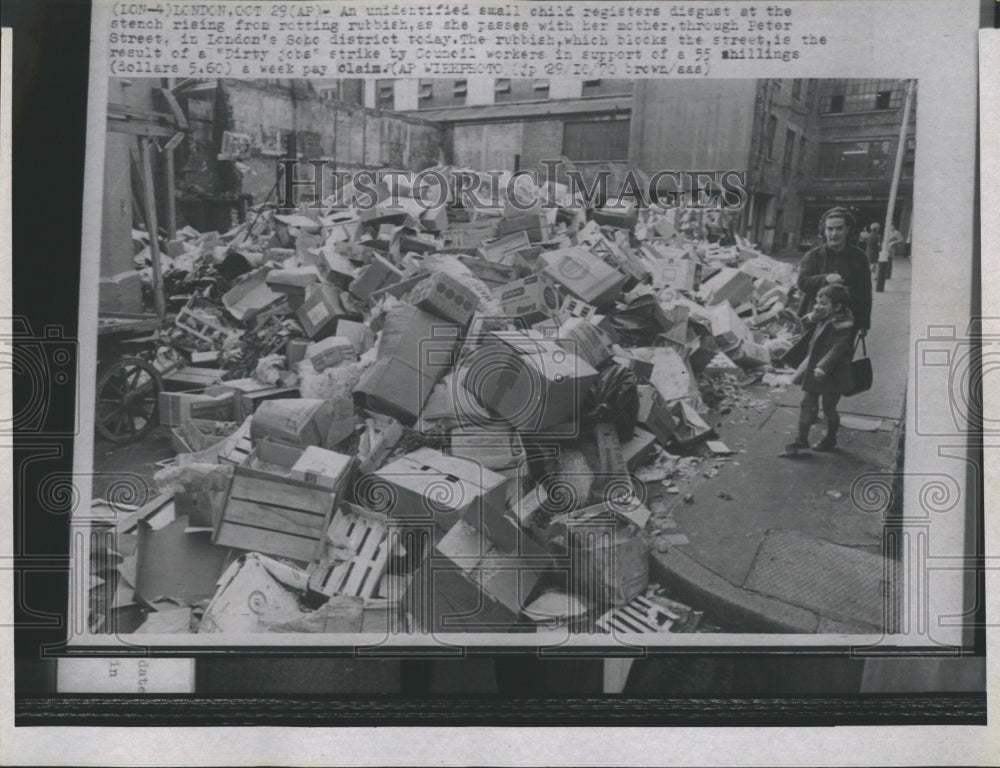 Press Photo Child Shows Replusion at Pile of Trash in England - Historic Images