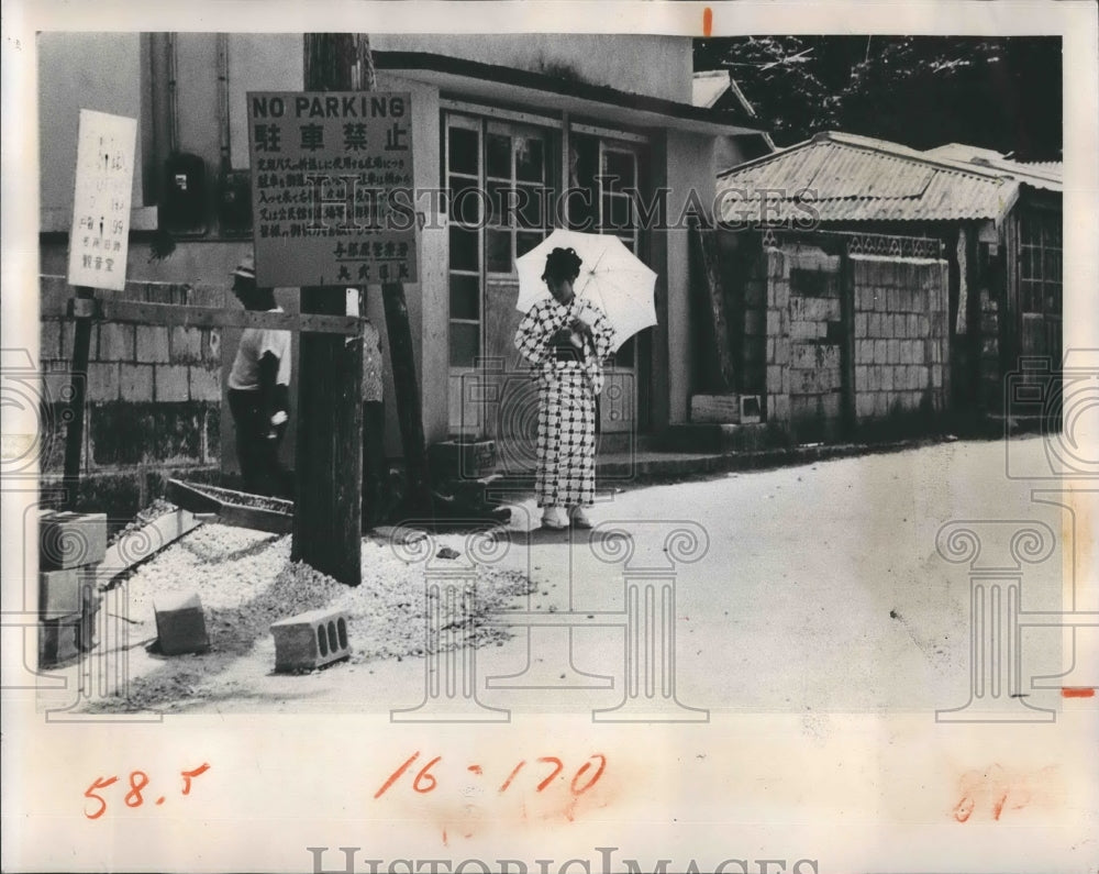 1969 Press Photo Unidentified girl waits for a bus by a street in Okinawa - Historic Images