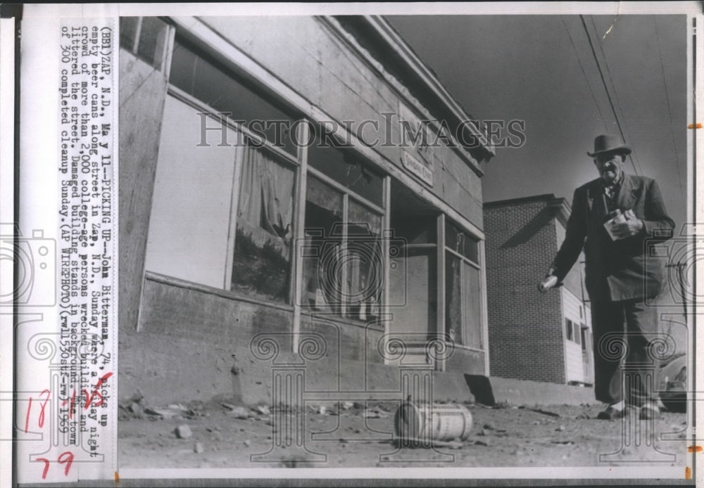 1969 Press Photo John Bitterman, 74 picks up beer cans along street in Zap, ND, - Historic Images