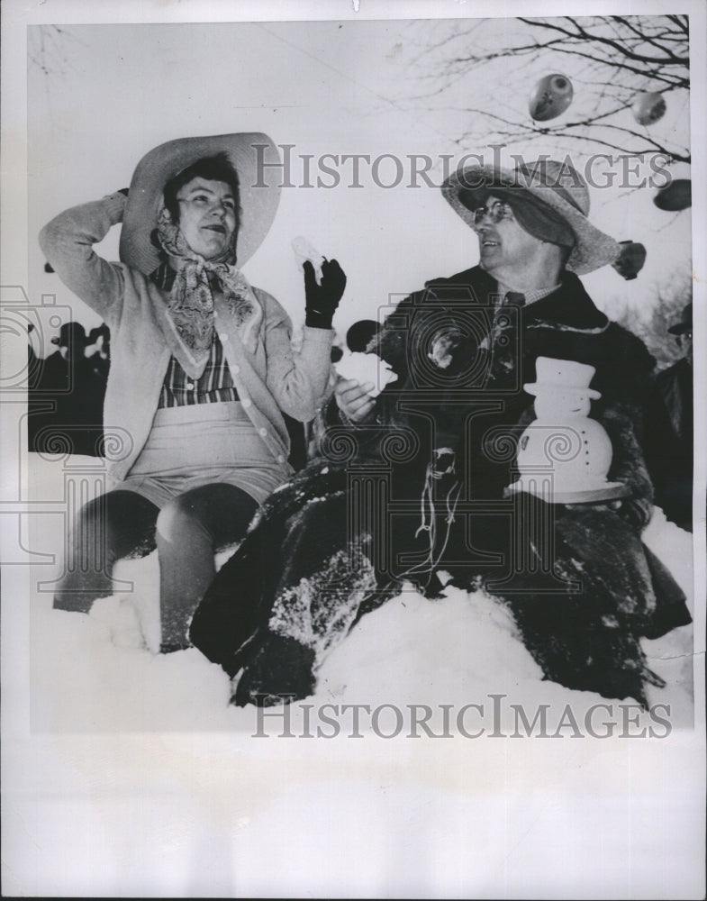 1950 Press Photo Mrs.Gus Glasrud and Gilbert sit on the snow on picnic ground. - Historic Images