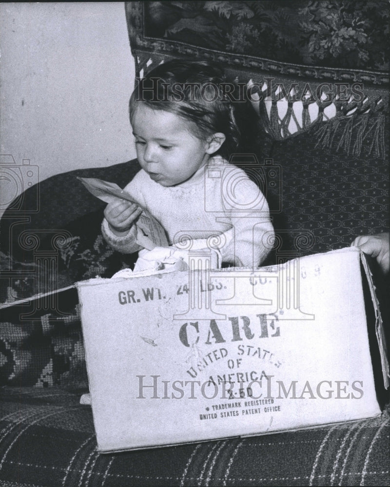 1961 Press Photo German Refugee Baby holds a CARE Food Crusade Package. - Historic Images