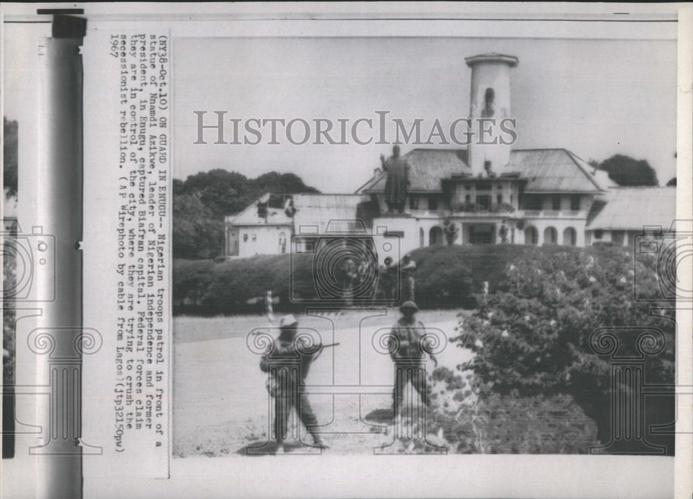 1967 Nigerian troops patrol in front of a statue of former President - Historic Images