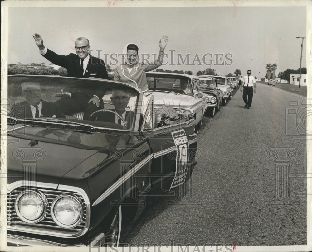 1964 Sen. and Mrs John Matthews wave from motorcade. - Historic Images