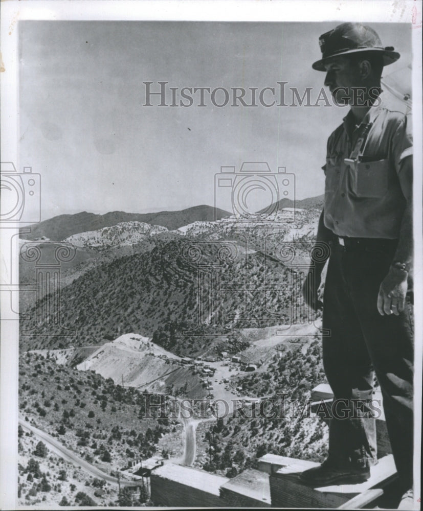 1961 A workman standing above a Nevada atomic testing site. - Historic Images