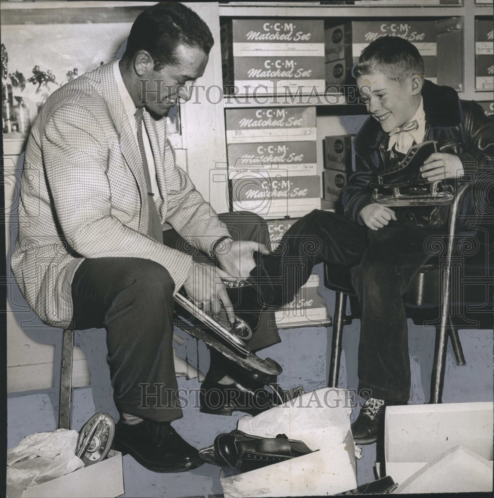 1957 don Rigazio salesman tries skates on Stephen O&#39;Keefe. - Historic Images