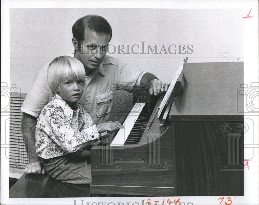 1976 Brad McMillian gets a piano lesson from his dad Herb - Historic Images