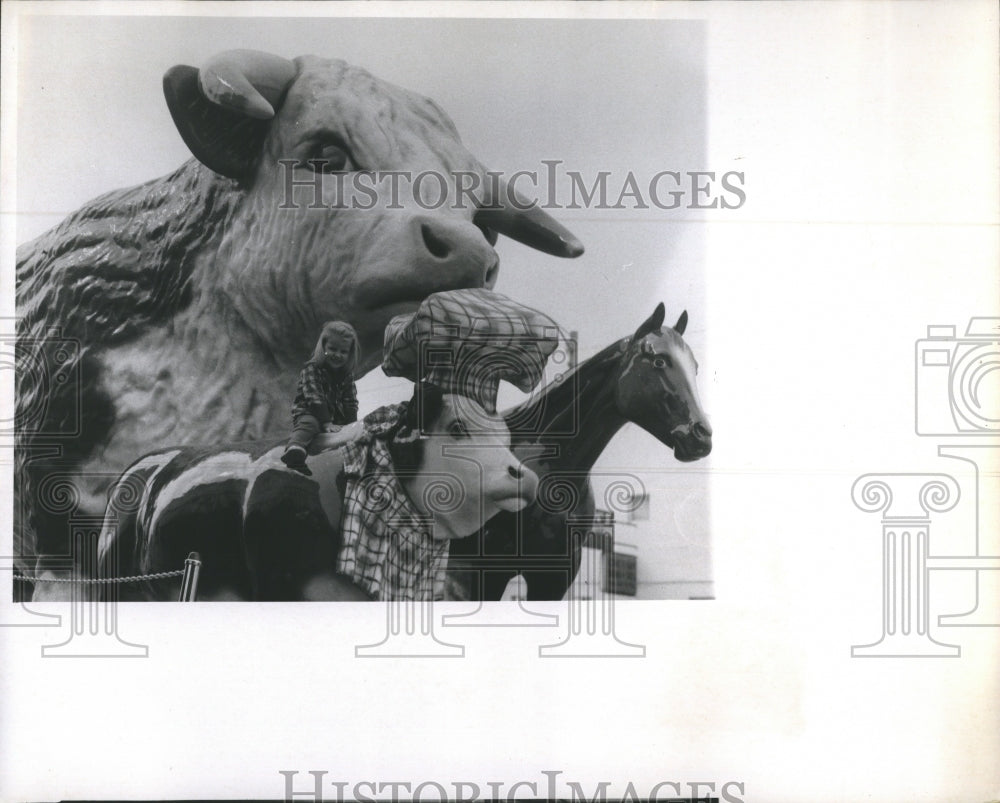 1969 Teresa Anne Brennan sitting on the sculpture of a bull - Historic Images