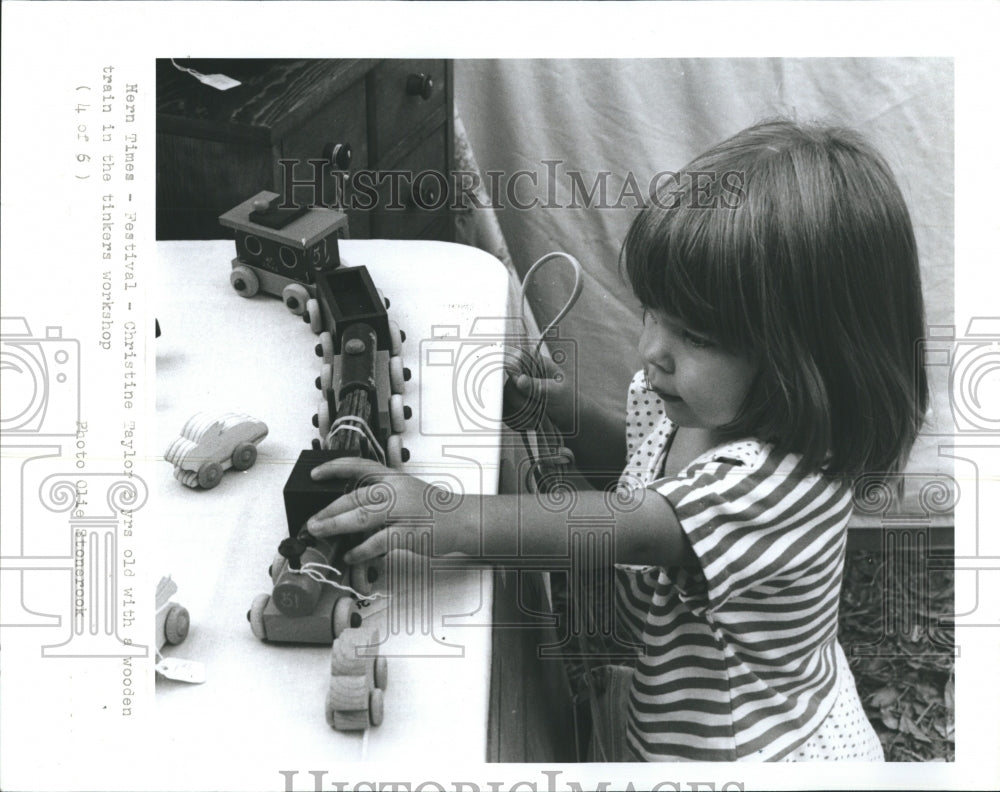 1990 Christine Taylor looks at wood train.  - Historic Images