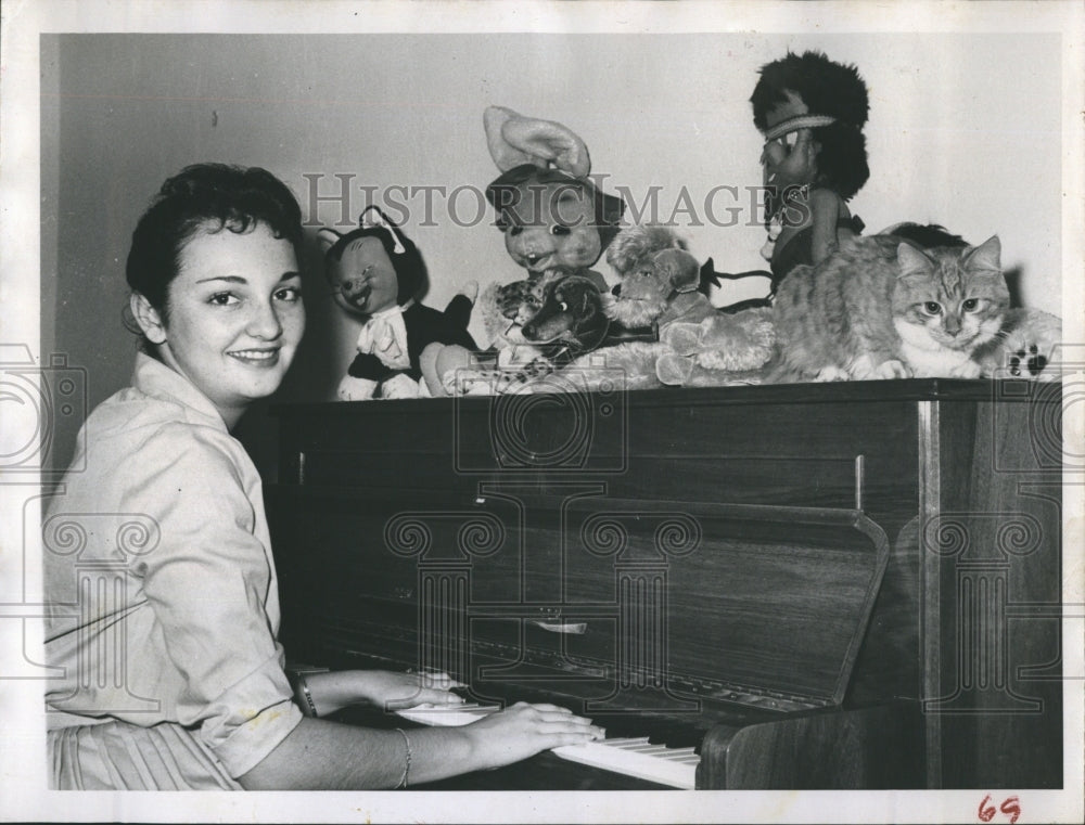 1960 Priscilla Demo playing piano as Cuddles the cat reclines - Historic Images