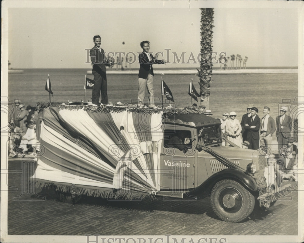 Press Photo Men ride atop the roof of a vehicle during a festival - Historic Images