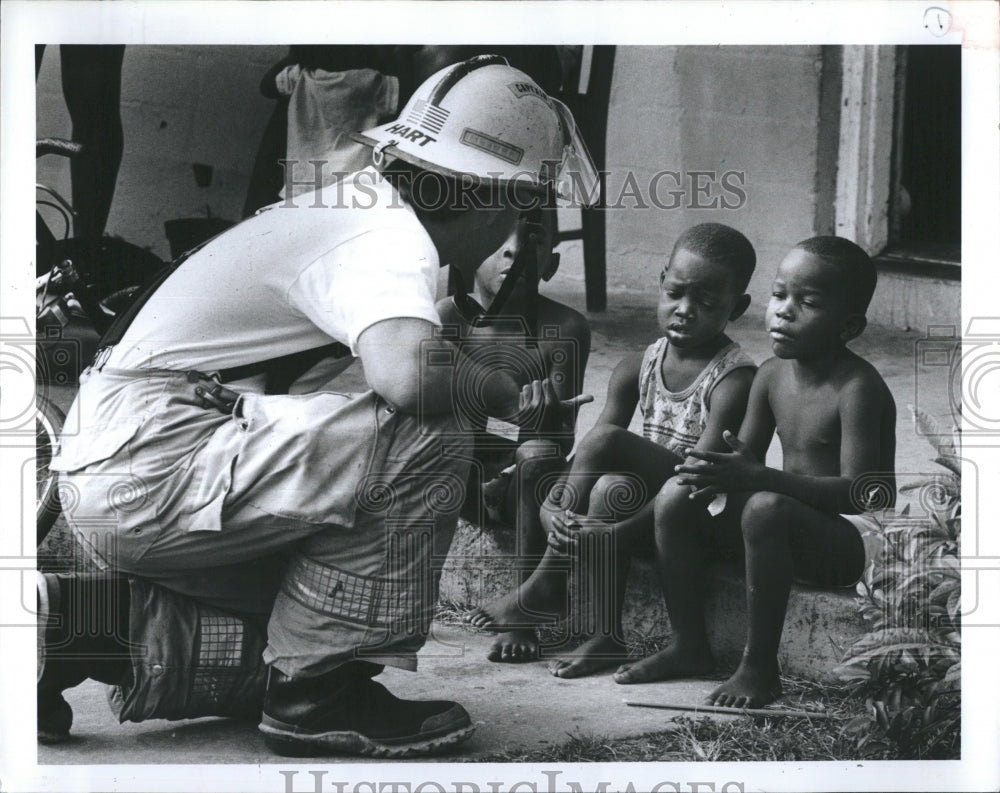 1991 Fire Captain Toby Hart chatting with boys from apt. fire, Tampa - Historic Images