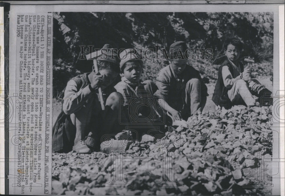 1970 Nepalese and Tibetan refugee and children use hammers to - Historic Images