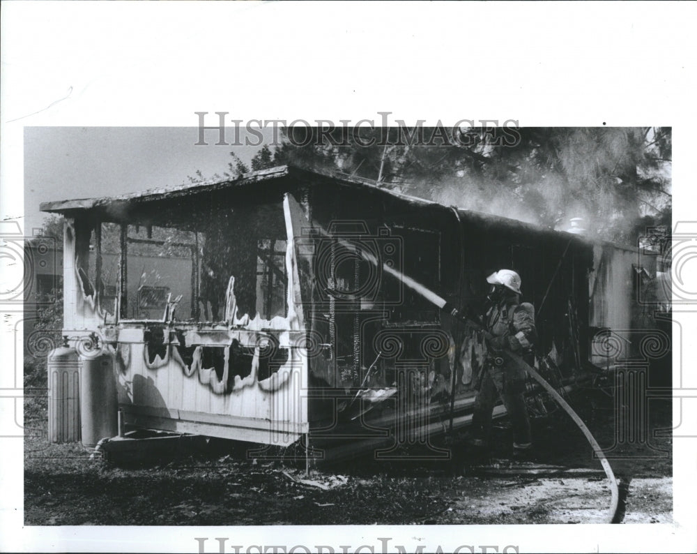 1988 Press Photo Largo firefighter sprays water mobile home caught fire - Historic Images