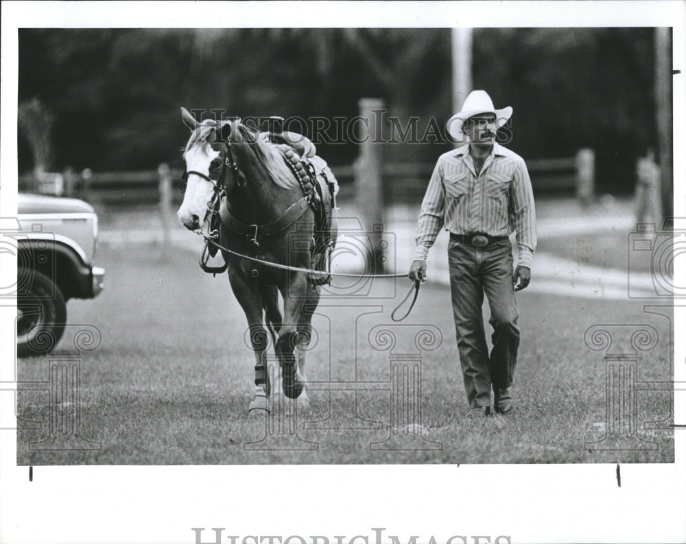 1990 A cowboy and his horse head to the ring - Historic Images