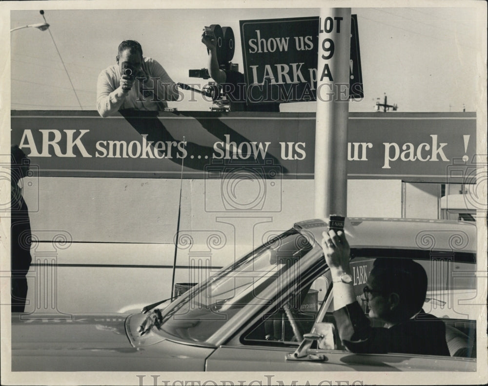 1966 Press Photo Motorist held up his Lark Pack Cigarette. - RSJ01623 - Historic Images