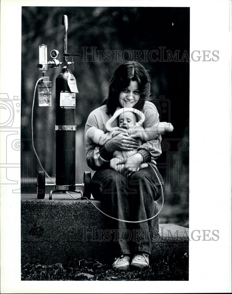 1984 Press Photo Baby Daniel Helms with portable oxygen tank with her Mother. - Historic Images