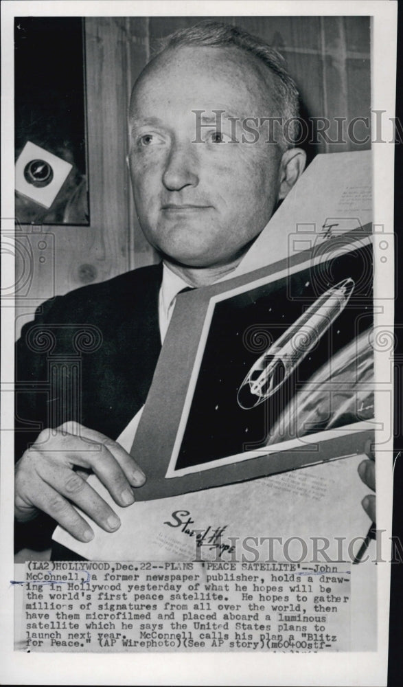 John McConnell holds a  drawing of world's first peace satellite.-Historic Images