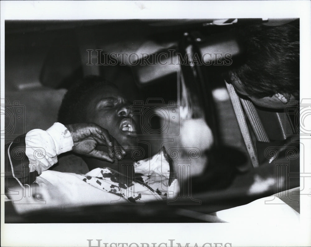 1990 Press Photo Damien Jones Shotgun Shooting Victim aided at Scene - Historic Images