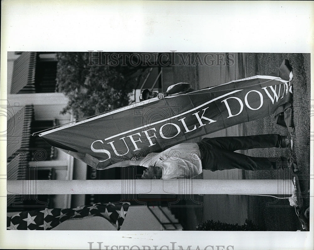 1996 Press Photo Suffolk Downs grounds crew hoist new flags in race track - Historic Images