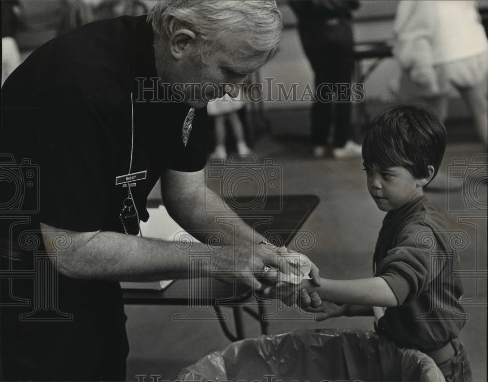 1983, Officer Garry Bailey Cleans Christopher Holley&#39;s Hands, Alabama - Historic Images