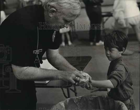 1983, Officer Garry Bailey Cleans Christopher Holley's Hands, Alabama - Historic Images