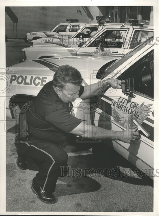 1985 Press Photo Homewood, Alabama officer Roy Olney putting decal on police car - Historic Images