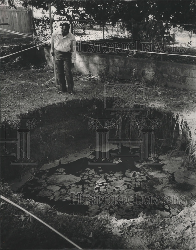 1988 Press Photo Johnny Collins views sink hole in his backyard, Ensley, Alabama - Historic Images