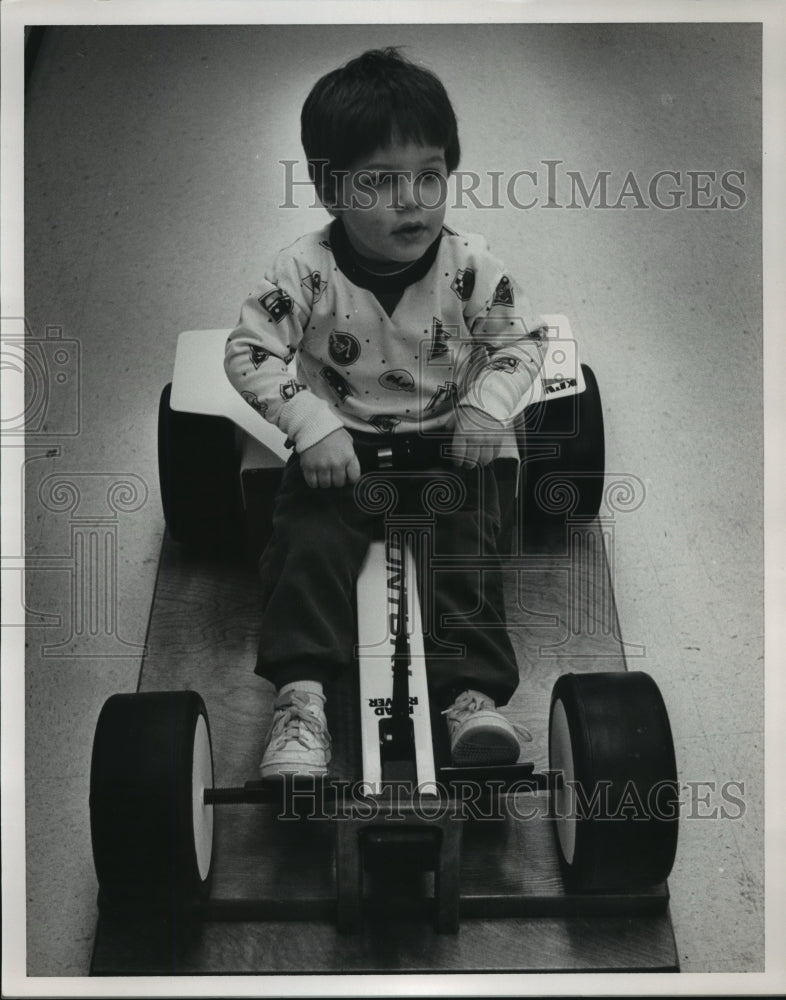 1987 Gregory Bernstein on children's rowing machine, Alabama - Historic Images