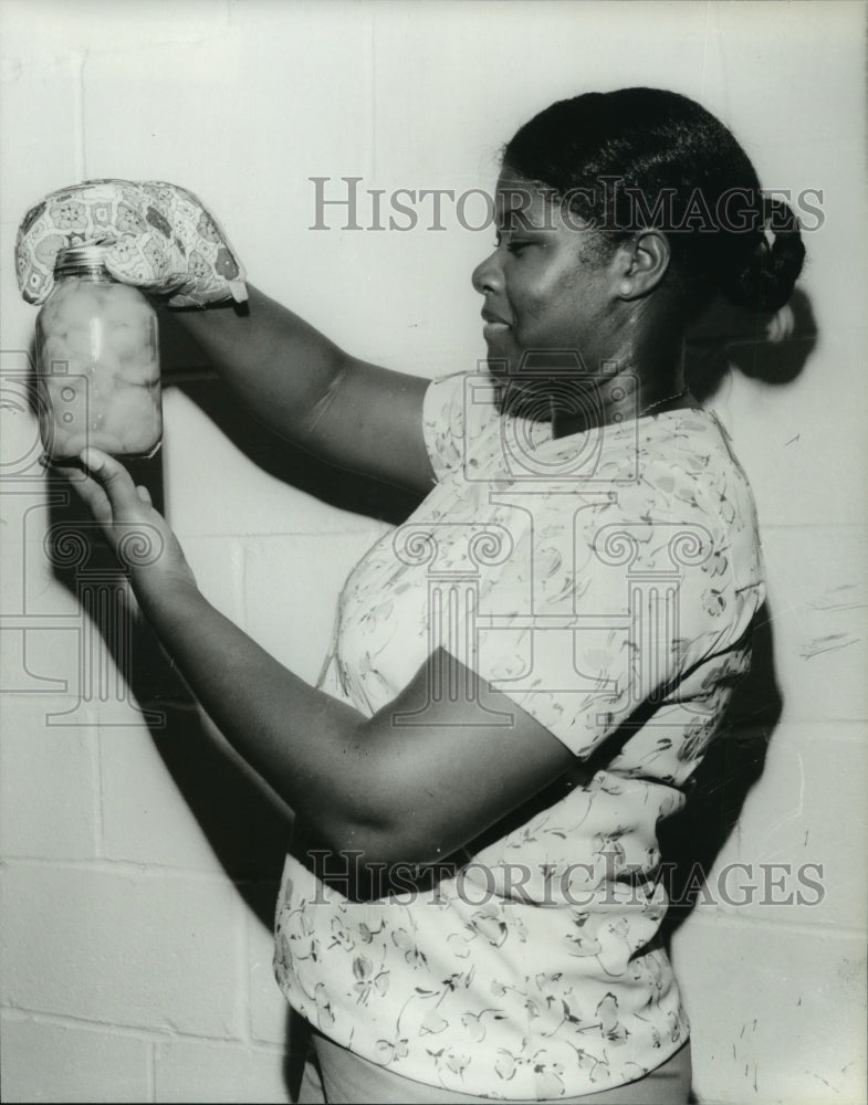 1981 Emma Scruggs inspects jar of canned peaches, Hillsboro, Alabama - Historic Images