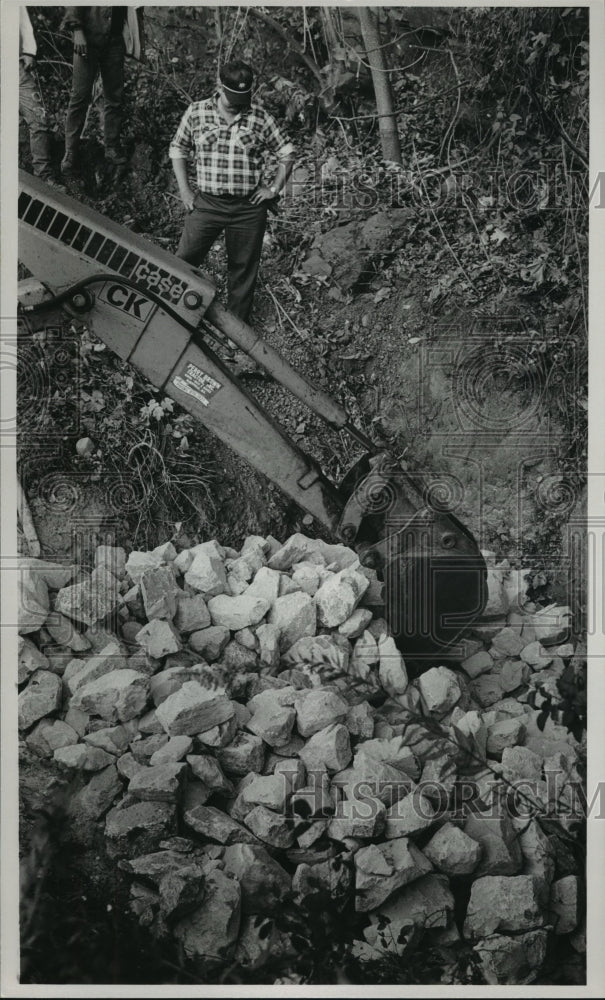 1987 Lanny Nelson watches rock being placed in abandoned mine shaft - Historic Images